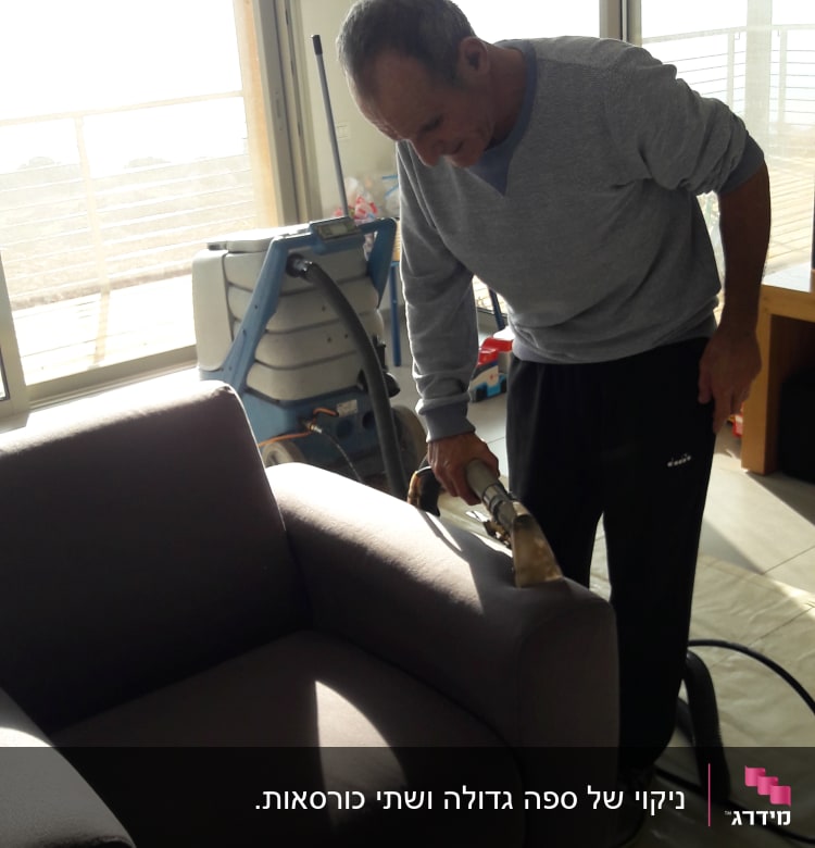 אדם מנקה ספה עם מכשיר ניקוי מקצועי